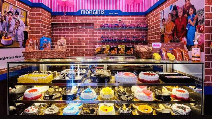 Display counter filled with decorated cakes under a Monginis sign